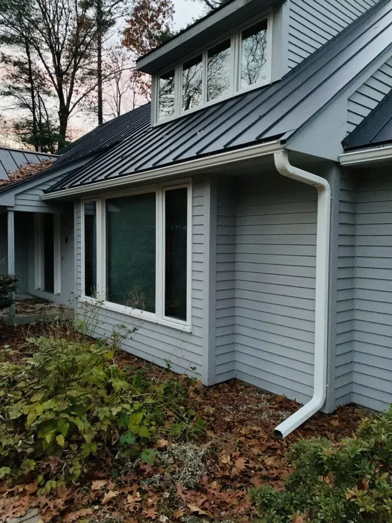 White seamless gutters on a gray home with metal roofing