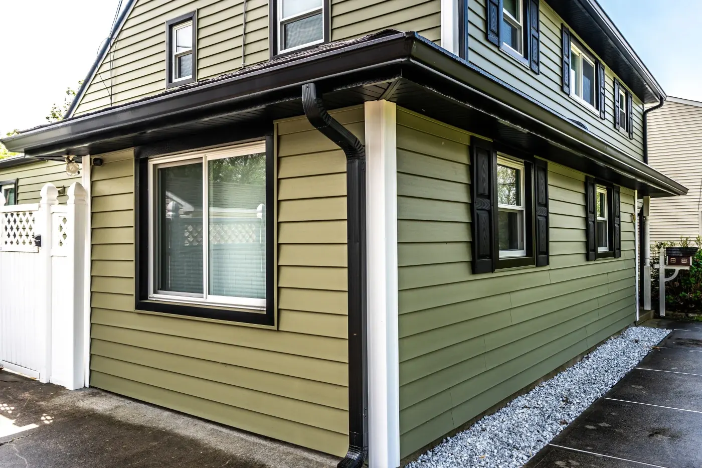 Black seamless gutters and downspout on a green-sided home