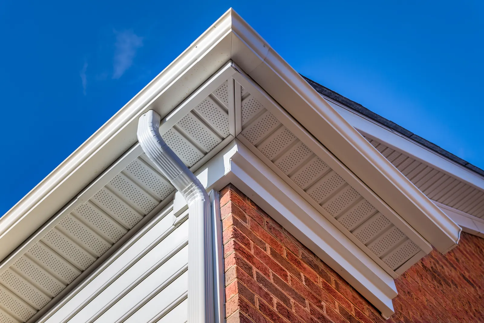 White gutter aligned with fascia and vented soffit above brick